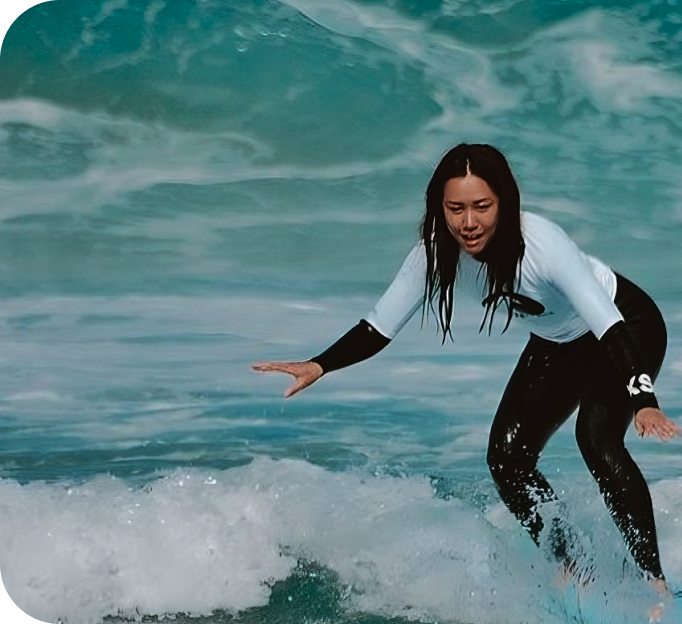Mujer en traje de neopreno surfeando en el océano.